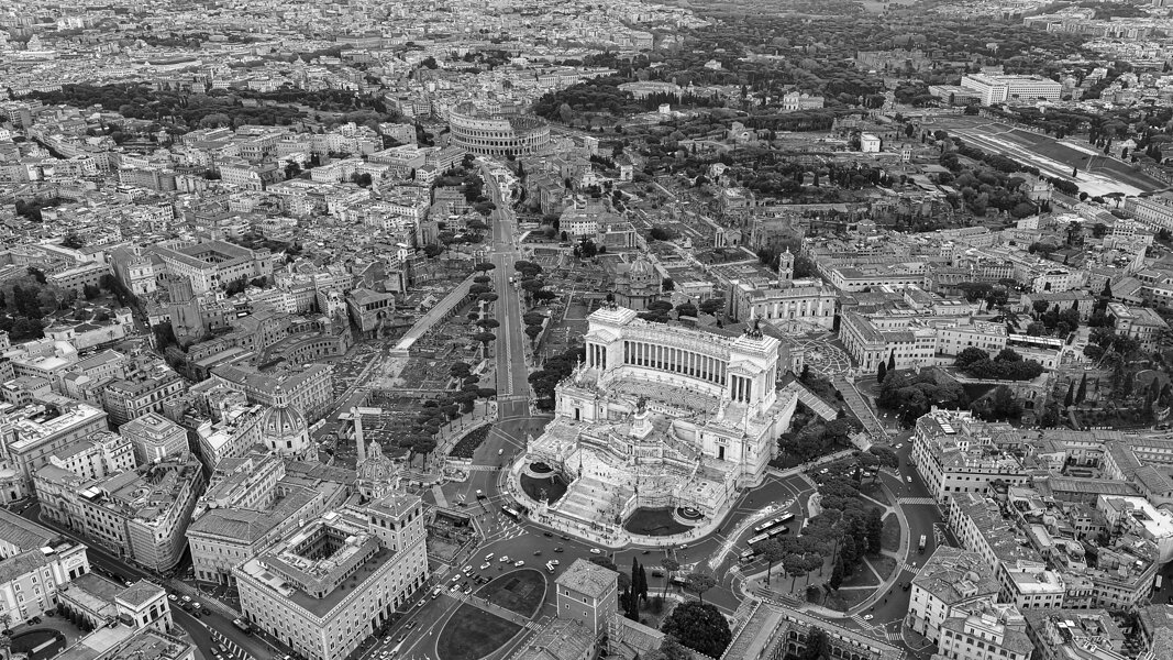 Aerial view of Altar of the Fatherland by Piazza Venezia and Colosseum in Rome, Italy. Flying drone view of white marble memorial monument and above view of iconic ancient national landmarks